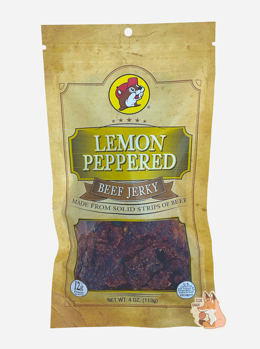 A picture of the front of a tan plastic bag of Buc-ee's Lemon Pepper Beef Jerky.  The logo is in yellow with white text.  The label underneath reads 'Made From Solid Strips Of Beef'.A small window on the bottom of the bag shows the dark brown/red dried jerky inside.  The bag has a picture of Buc-ee the Beaver on it.