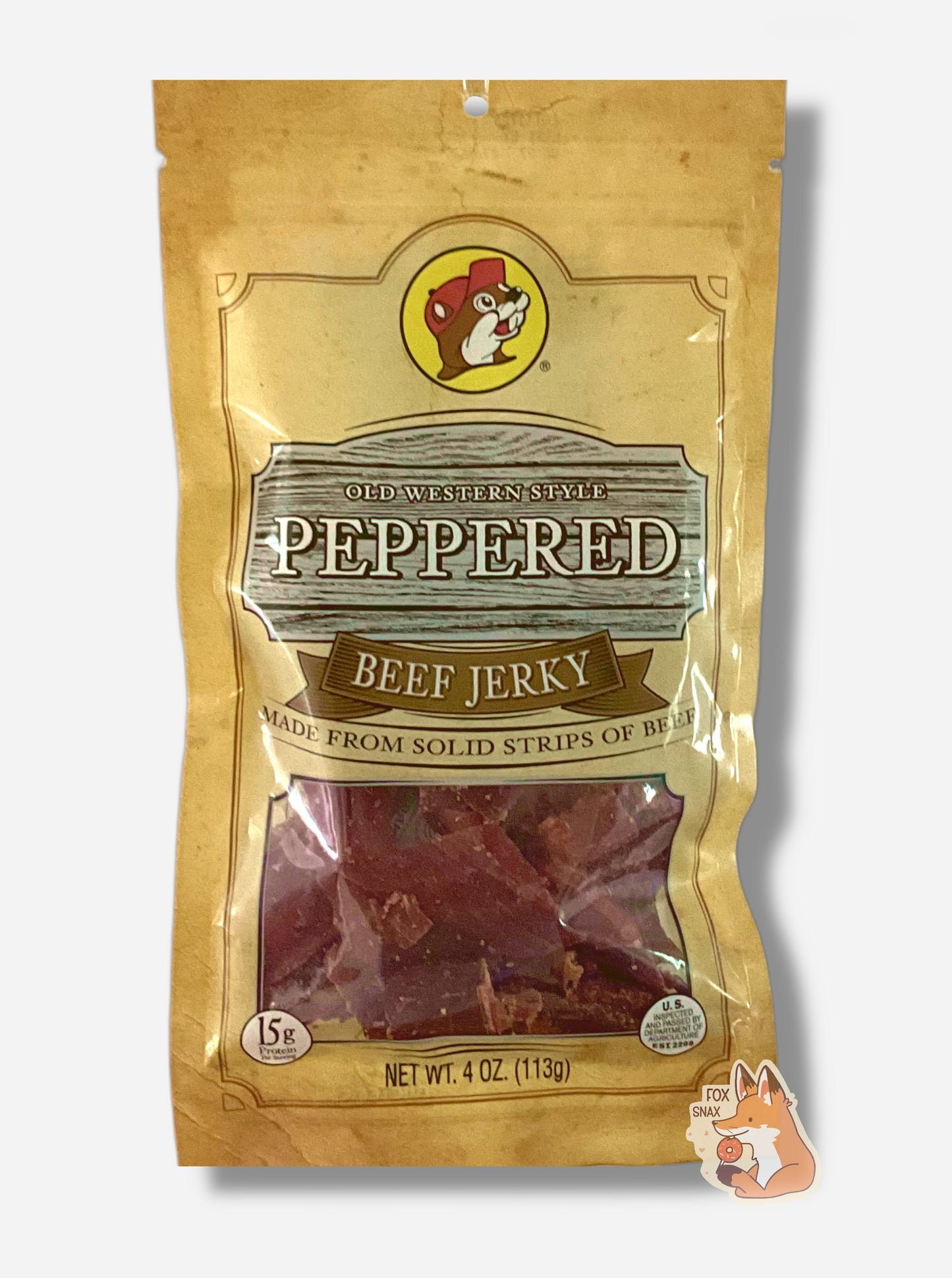 A picture of the front of a tan plastic bag of Buc-ee's Old Western Style Peppered Jerky.  The logo is in brown with white text.The label underneath reads 'Made From Solid Strips Of Beef'. A small window on the bottom of the bag shows the red dried jerky inside.  The bag has a picture of Buc-ee the Beaver on it.