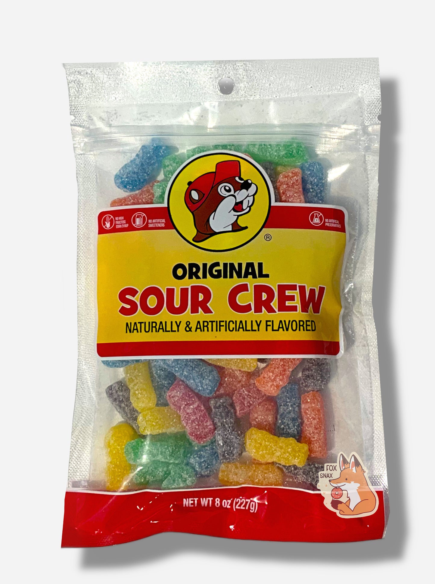 A picture of the front of a resealable bag of Buc-ee's Original Sour Crew, which are red, orange, yellow, green, blue, and purple sour and sweet sorta-human-shaped candies.  The bag reads ORIGINAL SOUR CREW, Naturally & Artificially Flavored, and has a picture of Buc-ee the Beaver on it.  The candies inside are coated in large white grains of sugar and sour powder.