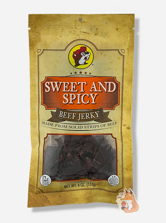 A picture of the front of a tan plastic bag of Buc-ee's Sweet And Spicy Beef Jerky.  The logo is in orange with white text.  The label underneath reads 'Made From Solid Strips Of Beef'.A small window on the bottom of the bag shows the dark brown/red dried jerky inside.  The bag has a picture of Buc-ee the Beaver on it.