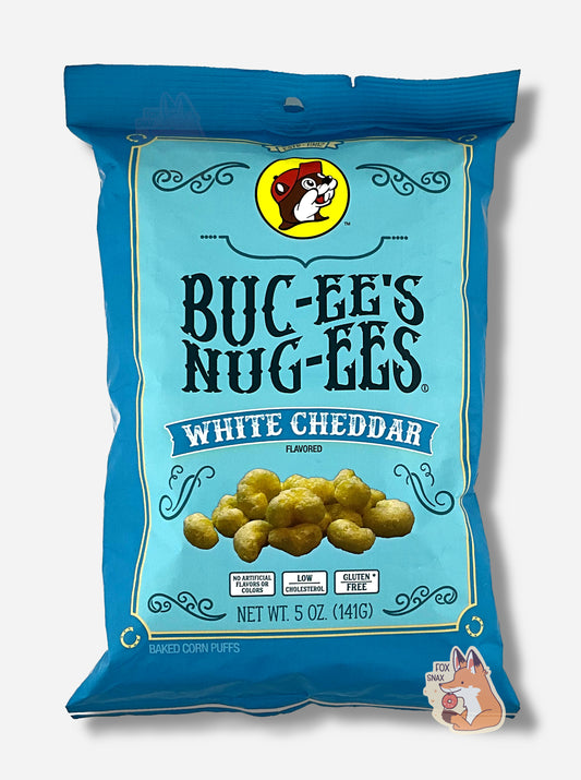 A picture of the front of a opaque, dark blue and light blue bag of Buc-ee's Nug-ees White Cheddar which are puffed corn snack with white cheddar flavor, and has a picture of Buc-ee the Beaver on it.  The bag reads White Cheddar Flavored, No Artificial Colors or Flavors, Low Cholesterol, Gluten Free, Baked Corn Puffs.