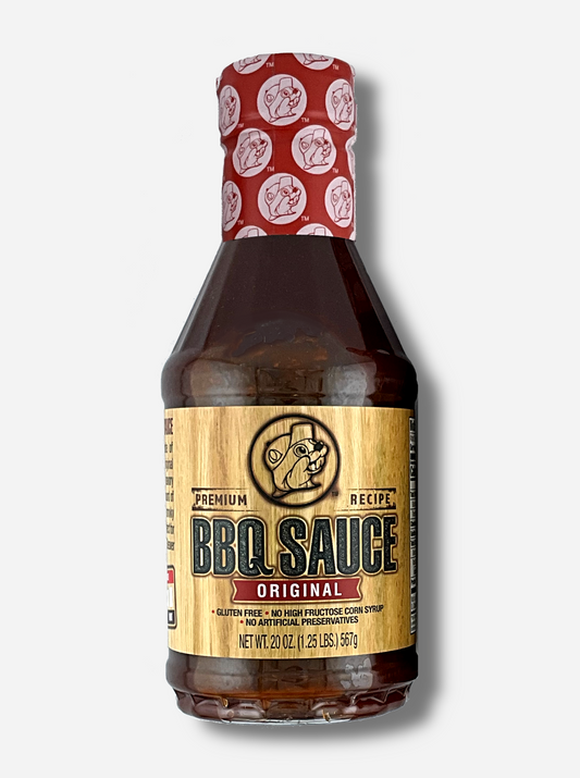 A plastic bottle of Buc-ee's Premium Recipe BBQ Sauce, Original.  The top of the bottle is sealed with a plastic wrap in red and white, dotted with Buc-ee's logos.  The BBQ label is a woodgrain, with a seared Buc-ee logo in the middle.  The rest of the bottle is clear, and dark red-brown bbq sauce can be seen.  The label reads: Gluten Free, No High Fructose Syrup, No Artificial Preservatives.