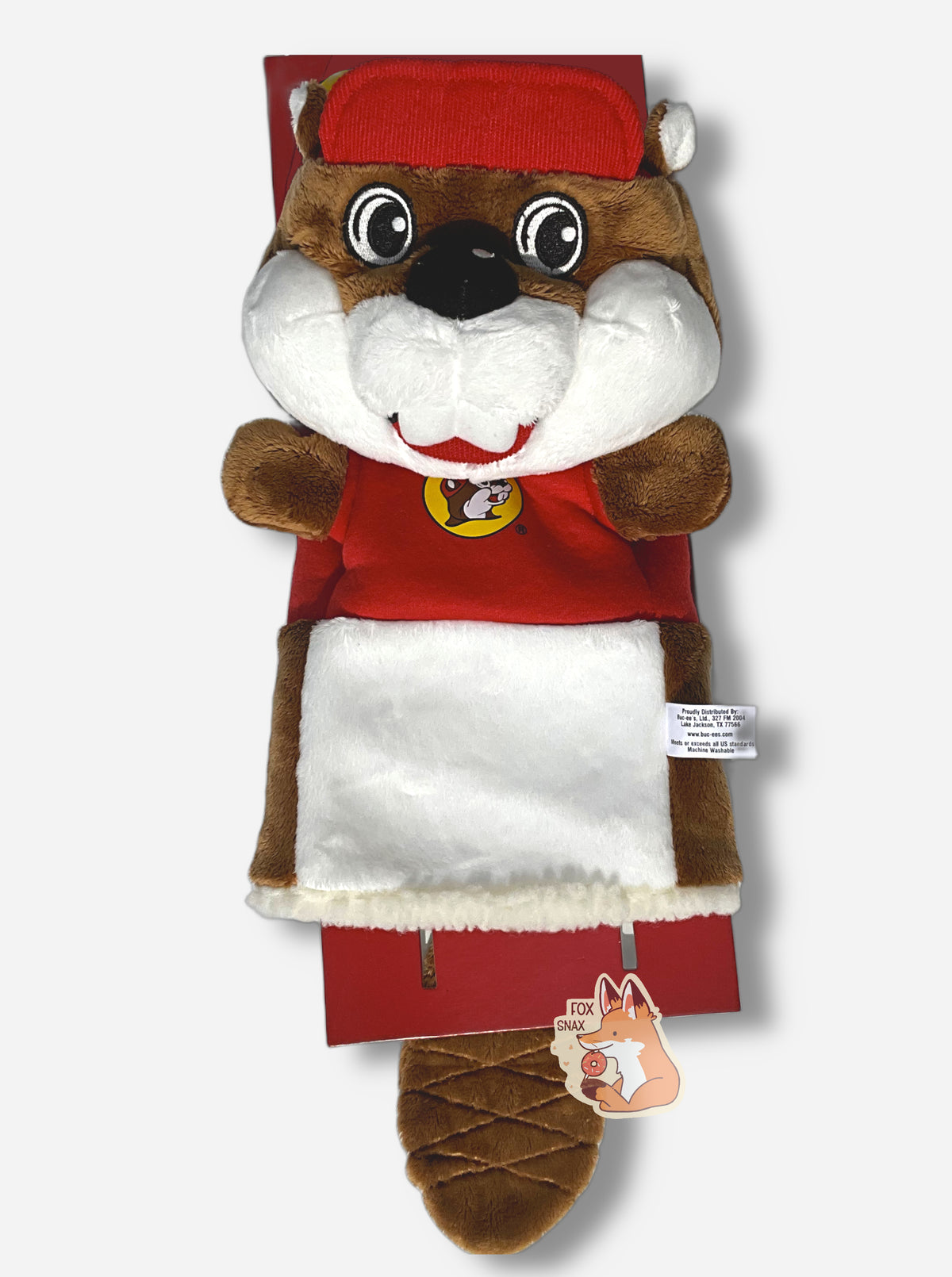 A Buc-ee the Beaver golf club headcover.  The head cover is of Buc-ee the beaver; a jolly cartoon beaver covered in brown and white fur, and has a big buck-tooth grin. On his head is a red ball cap, and he's wearing a red t-shirt with the Buc-ee's logo.  This golf club cover has no legs, but does have a fuzzy trim at the bottom to fit Buc-ee over a golf club.  A brown furred beaver tail can be seen hanging down from the backside.,