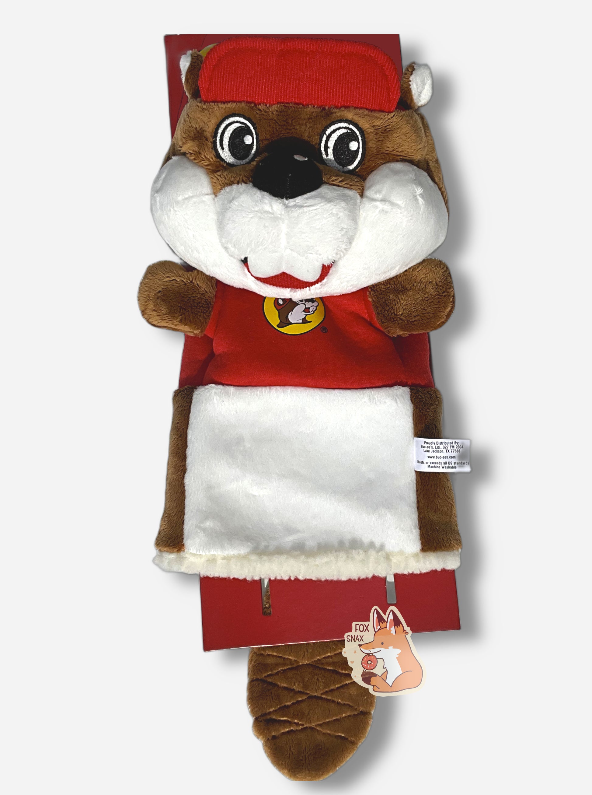 A Buc-ee the Beaver golf club headcover.  The head cover is of Buc-ee the beaver; a jolly cartoon beaver covered in brown and white fur, and has a big buck-tooth grin. On his head is a red ball cap, and he's wearing a red t-shirt with the Buc-ee's logo.  This golf club cover has no legs, but does have a fuzzy trim at the bottom to fit Buc-ee over a golf club.  A brown furred beaver tail can be seen hanging down from the backside.,