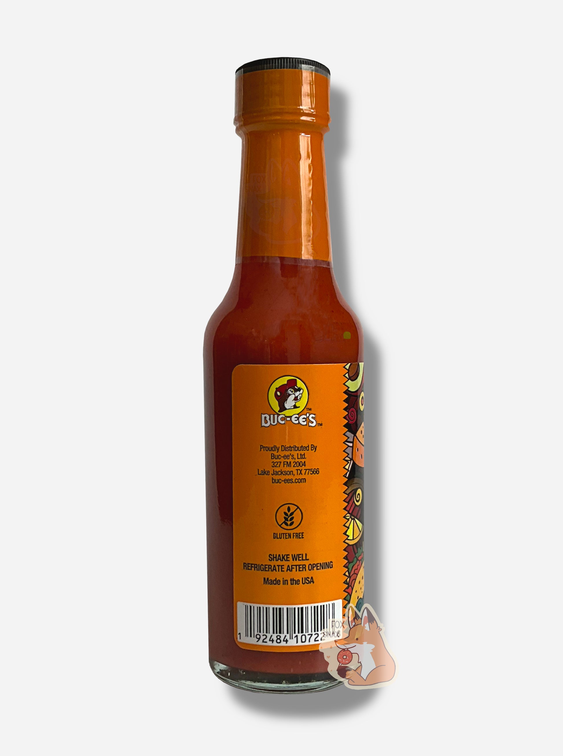 A picture of a small, tall glass bottle of hot sauce. The top of the bottle is sealed with an orange plastic top.  The back reads GLUTEN FREE, then SHAKE WELL and REFRIGERATE AFTER OPENING.  Made in the USA.  The sauce inside is orange/red.