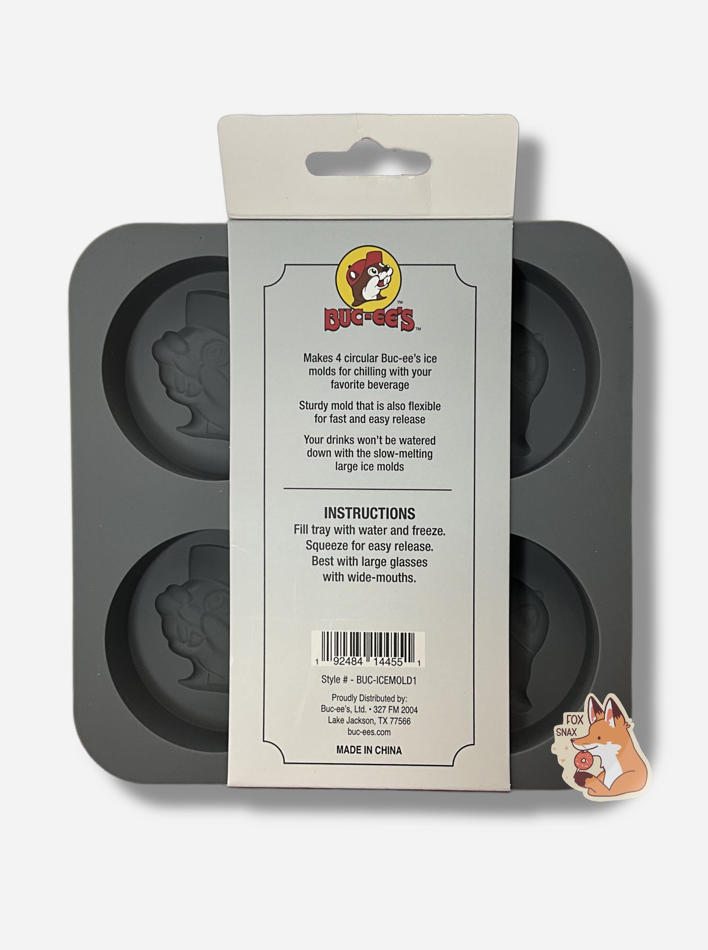 A picture of the back of a grey, floppy, ice mold tray  The tray is divided into four sections.  Each section contains a large circular imprint, shaped like the Buc-ee's icon - featuring Buc-ee The Beaver's Head, and has the icon with a cheerful grin, ballcap, and buck teeth.  The tag reads "Makes 4 circular Buc-ee's ice molds for chilling with your favorite beverage. Sturdy mold that is also flexible for fast and easy release. Your drinks won't be watered down with the slow-melting large ice molds".