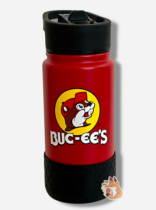 A picture of a small tie dye swirled cylindrical water bottle, with a giant Buc-ee The Beaver logo on the side; he's framed by a yellow background, and is wearing a red ball cap.  The surface of the water bottle is red paint over metal.  The top of the water bottle features a blue plastic handle with a flipstraw lid.  The bottom features a black plastic grippable bumper in a crosshatch pattern.