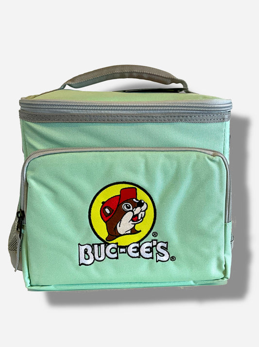 A picture of a front view of the front of a lunch box cooler.  The outer surface is made of mint-colored polyester with grey trim, and has a large mint-colored strap on it that reads BUC-EE'S.  The front of the lunch box has a zip pouch, with the Buc-ee's logo on it: a grinning beaver wearing a red hat against the background of a yellow circle.  The sides of the tote has mesh pouches, the top sealed by a zipper.