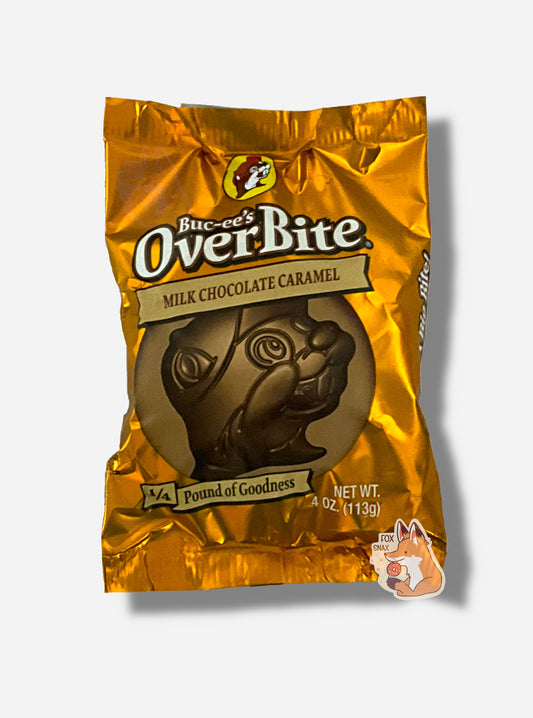 A picture of a package of a milk chocolate caramel Buc-ee's OverBite.  The package is metallic and orange/tan, and features a large picture of the candy, which is shaped like the Buc-ee's beaver mascot logo.  The package reads BUC-EE's OVERBITE, then MILK CHOCOLATE CARAMEL, then 1/4 POUND OF GOODNESS.