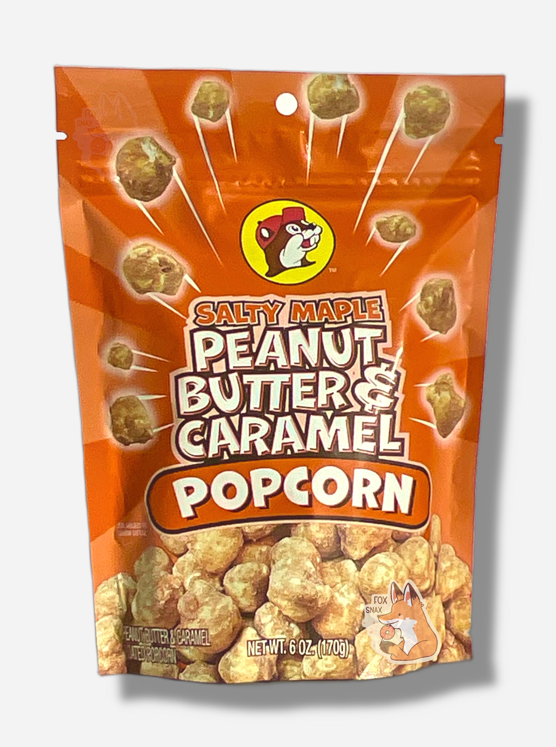 A picture of a orange/tan bag of Buc-ee's Salty Maple Peanut Butter & Caramel Popcorn.  The front of the bag has a group of popcorn nuggets, each coated in brown,  salty maple, peanut butter and caramel coating, exploding from the center.  A pile of popcorn is on the bottom.  The top center has the Buc-ee's logo, with cheerful beaver wearing a red ball cap, framed in a yellow circle, and reads SALTY MAPLE PEANUT BUTTER & CARAMEL POPCORN.