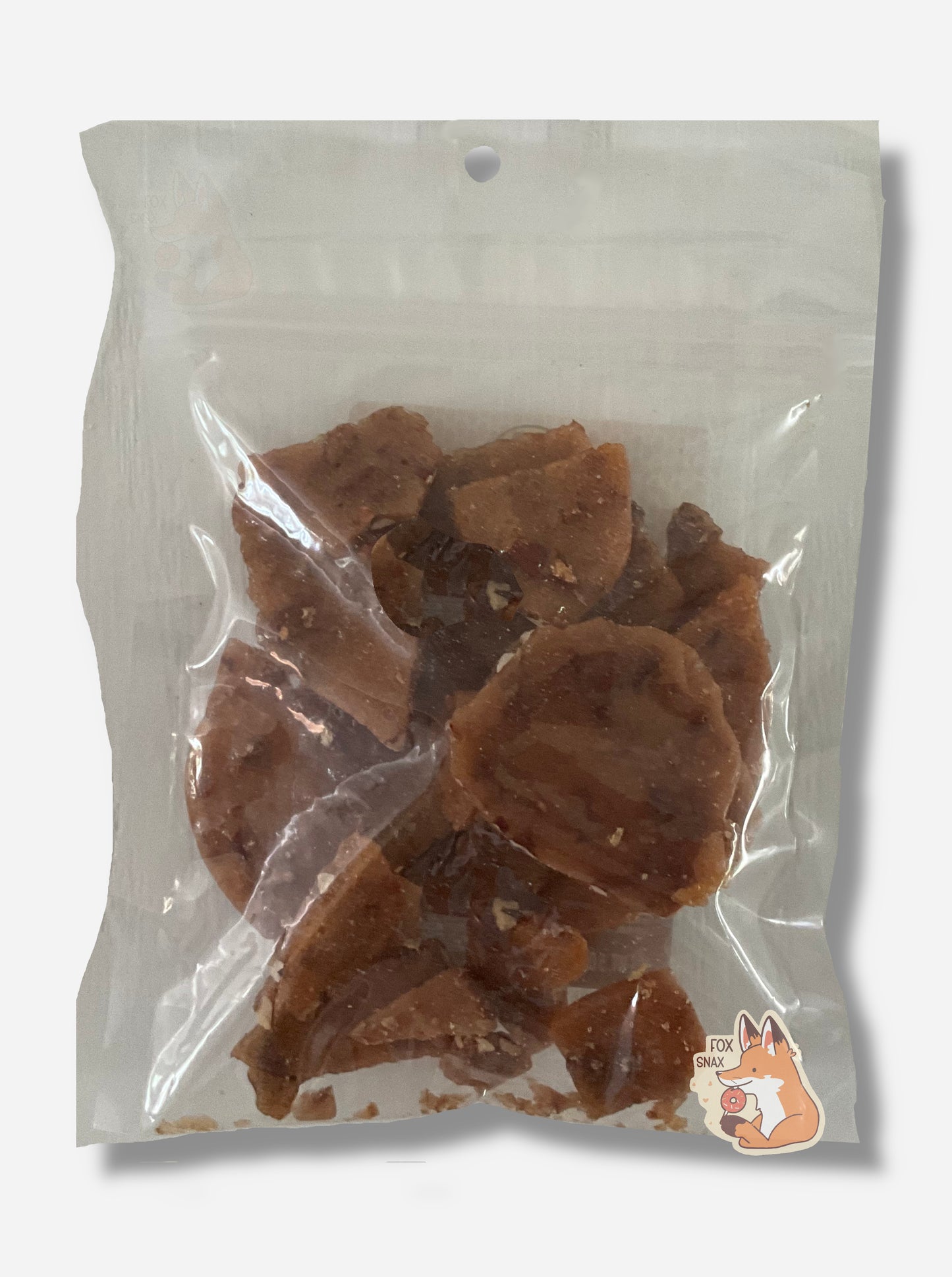 A picture of the back of a square clear plastic bag of Buc-ee's Old Fashioned Pecan Brittle.  Inside the plastic bag are brownish irregular pieces of brittle, intermittently dotted with pieces of pecan.