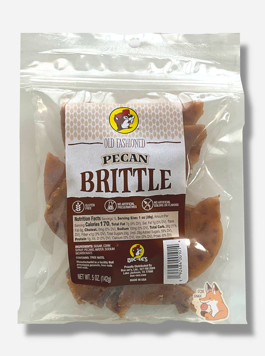 A picture of a square clear plastic bag of Buc-ee's Old Fashioned Pecan Brittle.  The bag has a red and brown rectangular sticker on it, and reads Old Fashioned Pecan Brittle, Gluten Free, No Artificial Preservatives, No Artificial Colors and Flavors.  Inside the plastic bag are brownish irregular pieces of  intermittently dotted with pieces of pecan.