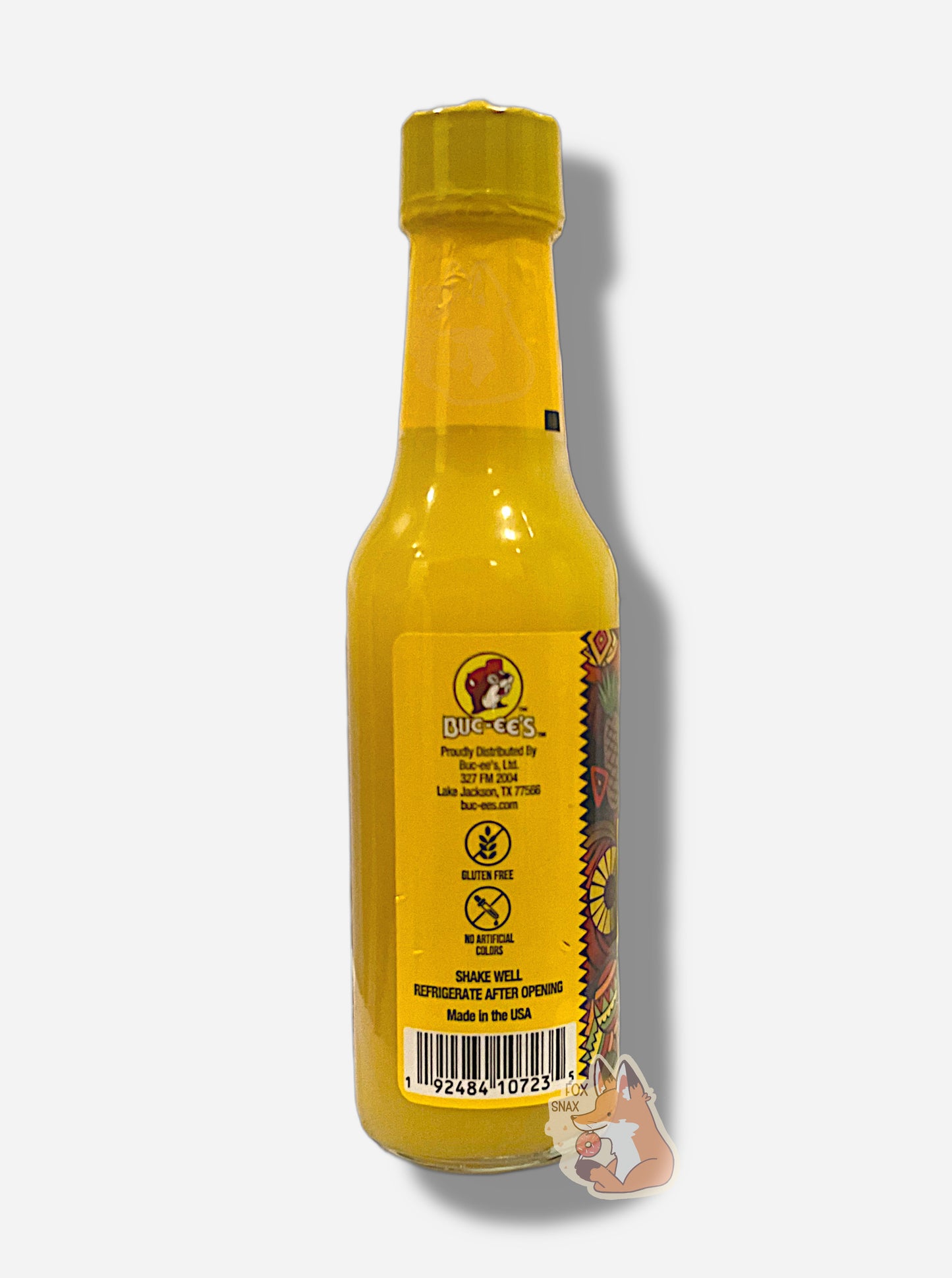 A picture of a small, tall bottle of hot sauce. The top of the bottle is sealed with a shiny yellow plastic top.  The back reads GLUTEN FREE,  NO ARTIFICIAL COLORS then SHAKE WELL and REFRIGERATE AFTER OPENING.  Made in the USA.  The sauce inside is bright yellow.
