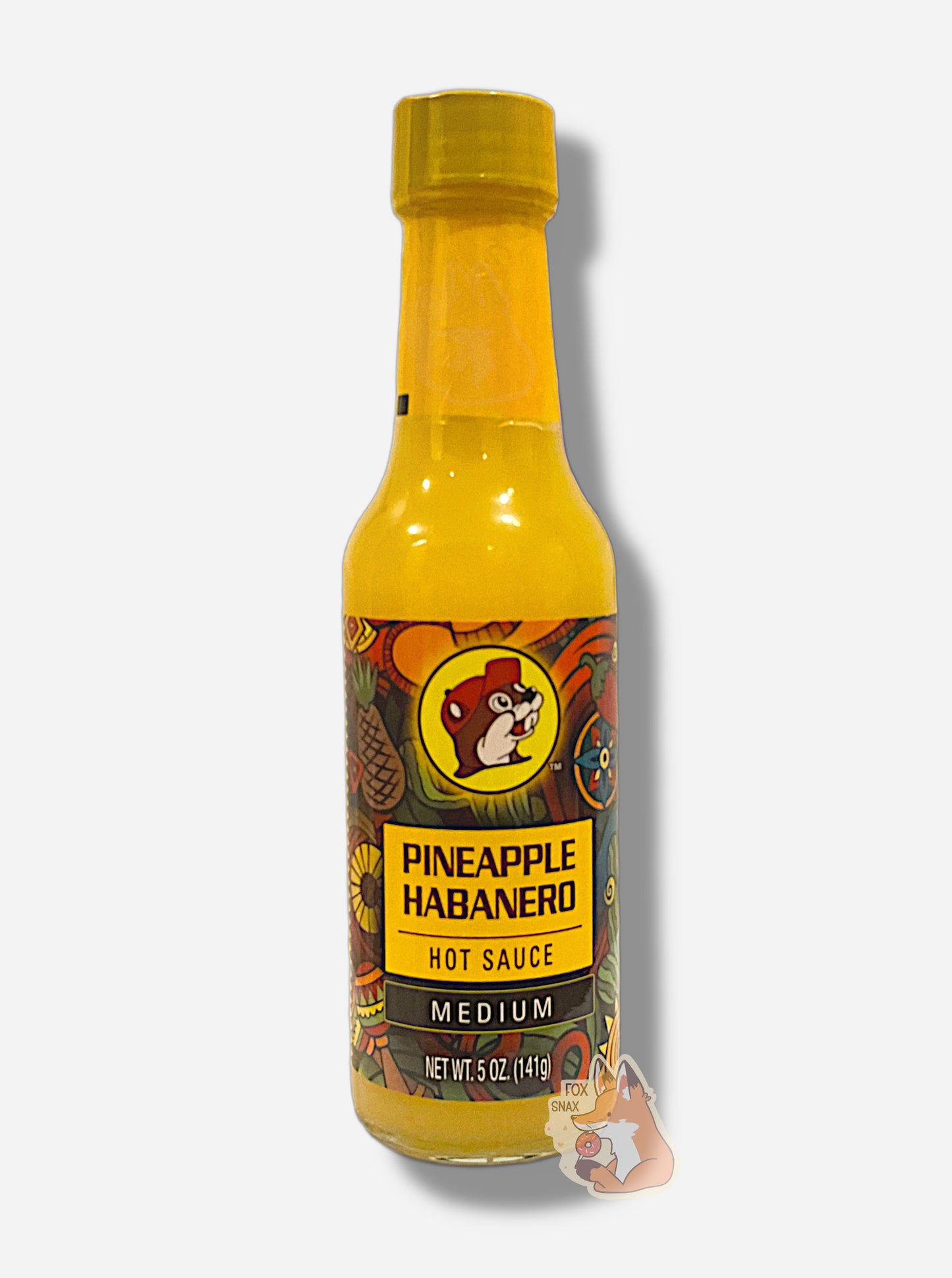 A picture of a small, tall glass bottle of hot sauce.  The top of the bottle is sealed with a plastic top.  The front label of the bottle reads PINEAPPLE HABANERO HOT SAUCE, MEDIUM.  The Buc-ee's logo can be seen on the front; the background is a fairly busy abstract artwork featuring an pineapple, sun, maracas, pepper, and several colorful abstract shapes.  The sauce inside is bright yellow, as is most of the packaging.