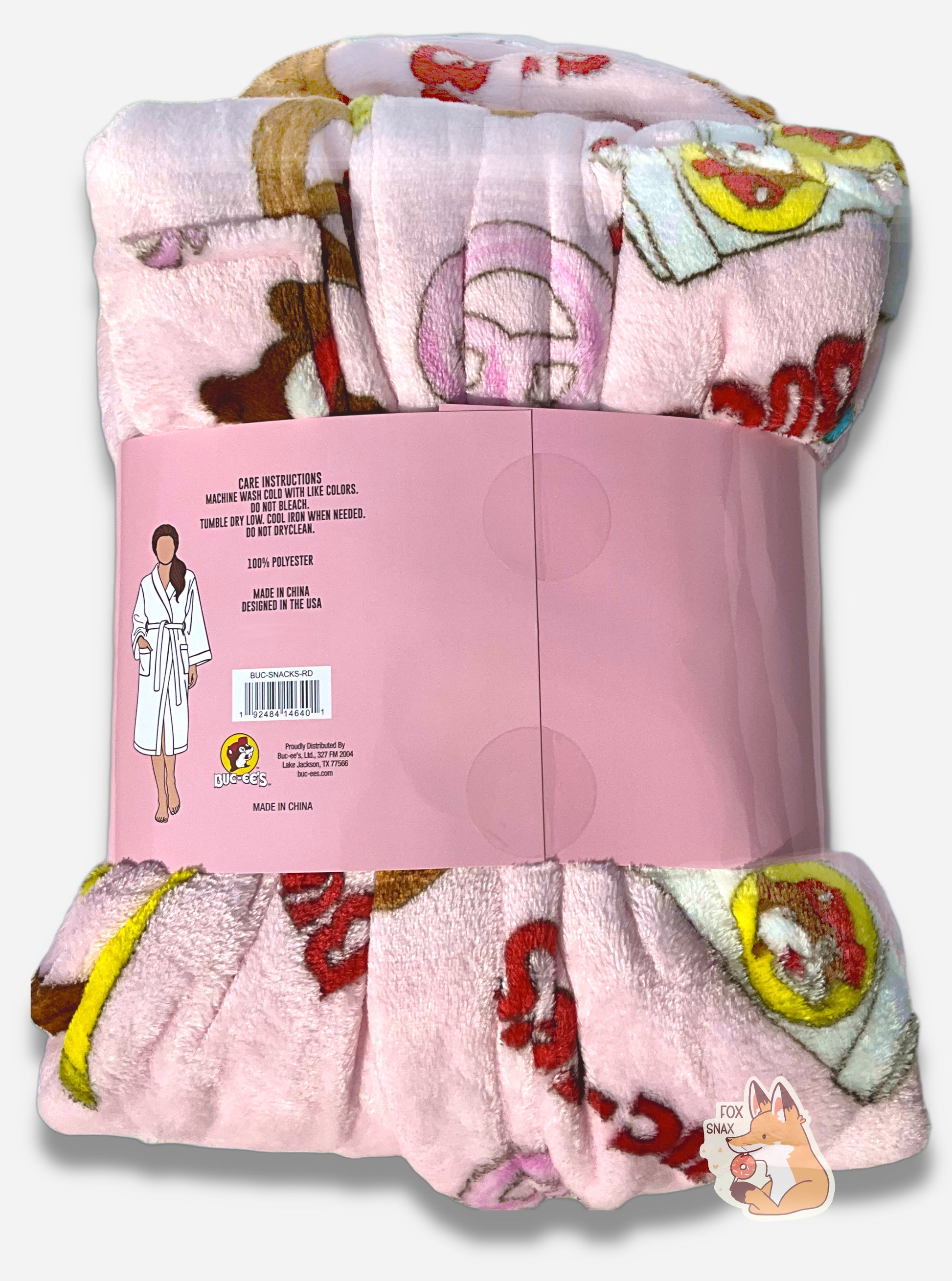 An image the back of a plush, wrapped, pink robe.  The surface is pink and fluffy, and is studded with blue and pink gummi bear pictures, drink cup picture, pretzels, brisket sandwiches, and the text "BUC-EE'S" in red and blue.  A cardboard wrapper around the "waist" of the robe shows the a picture of a woman wearing a representation of the robe, and reads "CARE INSTRUCTIONS", then "MACHINE WASH COLD WITH LIKE COLORS. DO NOT BLEACH. TUMBLE DRY LOW. COOL IRON WHEN NEEDED. DO NOT DRYCLEAN. 100% POLYESTER"