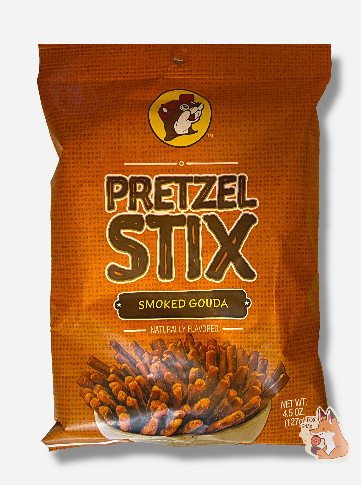 A picture of the front of an orange bag of Buc-ee's Pretzel Stix, Smoked Gouda flavor.  The bag reads NATURALLY FLAVORED.  At the top is the Buc-ee's logo - a cheerful beaver wearing a red ball cap.  The middle reads PRETZEL STIX in a brown font, then SMOKED GOUDA, then NATURALLY FLAVORED.  A large white bowl containg a plethora of coated pretzel sticks is on the bottom.