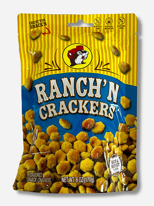 A picture of a metallic bag of Buc-ee's Ranch'N Crackers.  The logo is a blue background on white text; a large number of tan, savory-looking hexagonal oyster crackers are shown beneath it.  At the top is a picture of the logo of Buc-ee The Beaver, and it reads GREAT FOR SNACK'N, NO ARTIFICIAL COLORS, PRESERVATIVES, FLAVORS