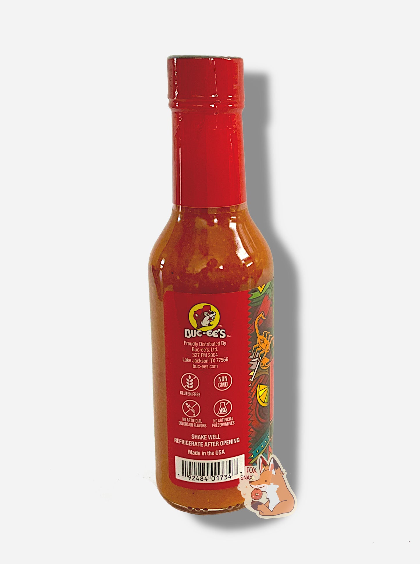 A picture of a small, tall bottle of hot sauce. The top of the bottle is sealed with a plastic top.  The back reads GLUTEN FREE, NON GMO, NO ARTIFICIAL COLORS OR FLAVORS, NO ARTIFICIAL PRESERVATIVES, then SHAKE WELL and REFRIGERATE AFTER OPENING.  Made in the USA.  The sauce inside is orange/red.