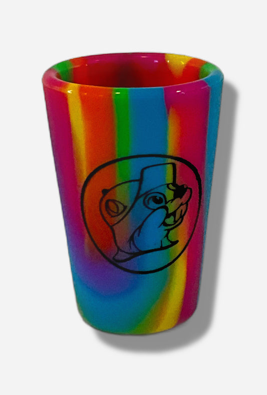 A picture of the front of silicone shot glass.  The material is streaky rainbow colors.  In the middle of the front is the Buc-ee's logo in black; it is a cheerful beaver wearing a ballcap, against a circle background. 