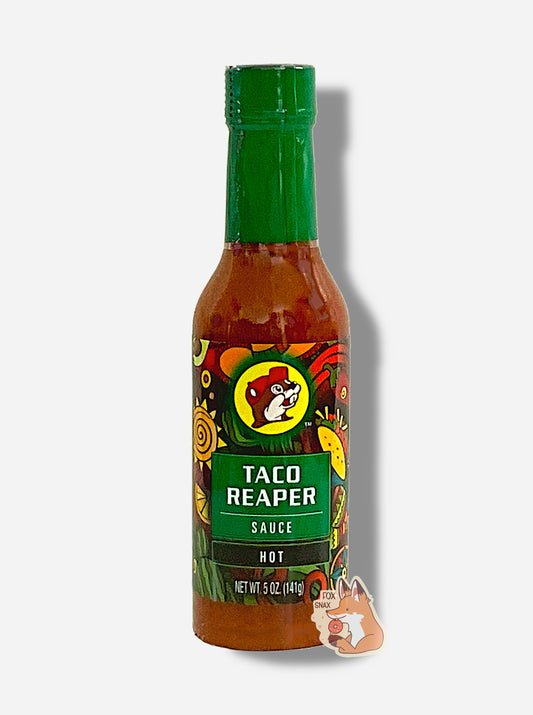 A picture of a small, tall glass bottle of hot sauce.  The top of the bottle is sealed with a plastic top.  The front label of the bottle reads TACO REAPER HOT SAUCE, HOT.  The Buc-ee's logo can be seen on the front; the background is a fairly busy abstract artwork featuring a cactus, two maracas, a lemon, a taco, and a red pepper.  The sauce inside is dark orange.