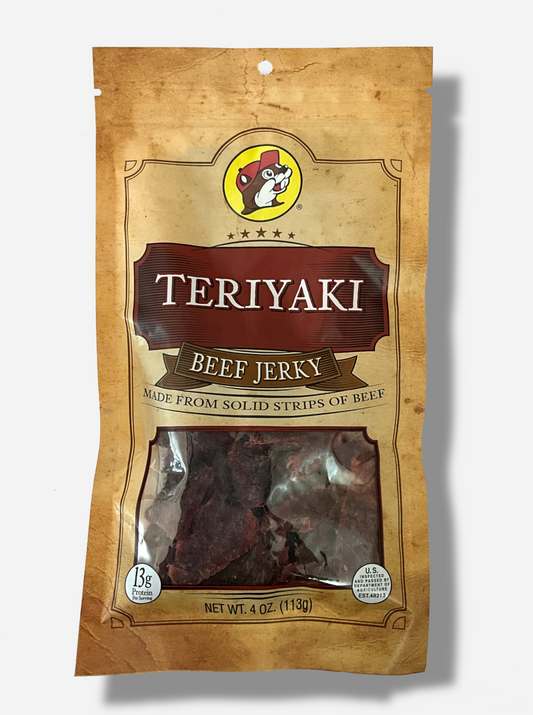 A picture of the front of a tan plastic bag of Buc-ee's Teriyaki Garlic Beef Jerky.  The logo is in red-brown with white text.The label underneath reads 'Made From Solid Strips Of Beef'.A small window on the bottom of the bag shows the dark brown/red dried jerky inside.  The bag has a picture of Buc-ee the Beaver on it.