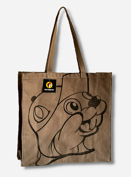 A picture of the front of a Buc-ee's Market Tote.  The tote is a large, cloth, rectangular. flat bag.  The front and back of the bag have a slightly faded black imprint of Buc-ee The Beaver's face.  Two large cloth straps are sewn to the top of the bag to make it easy to carry.