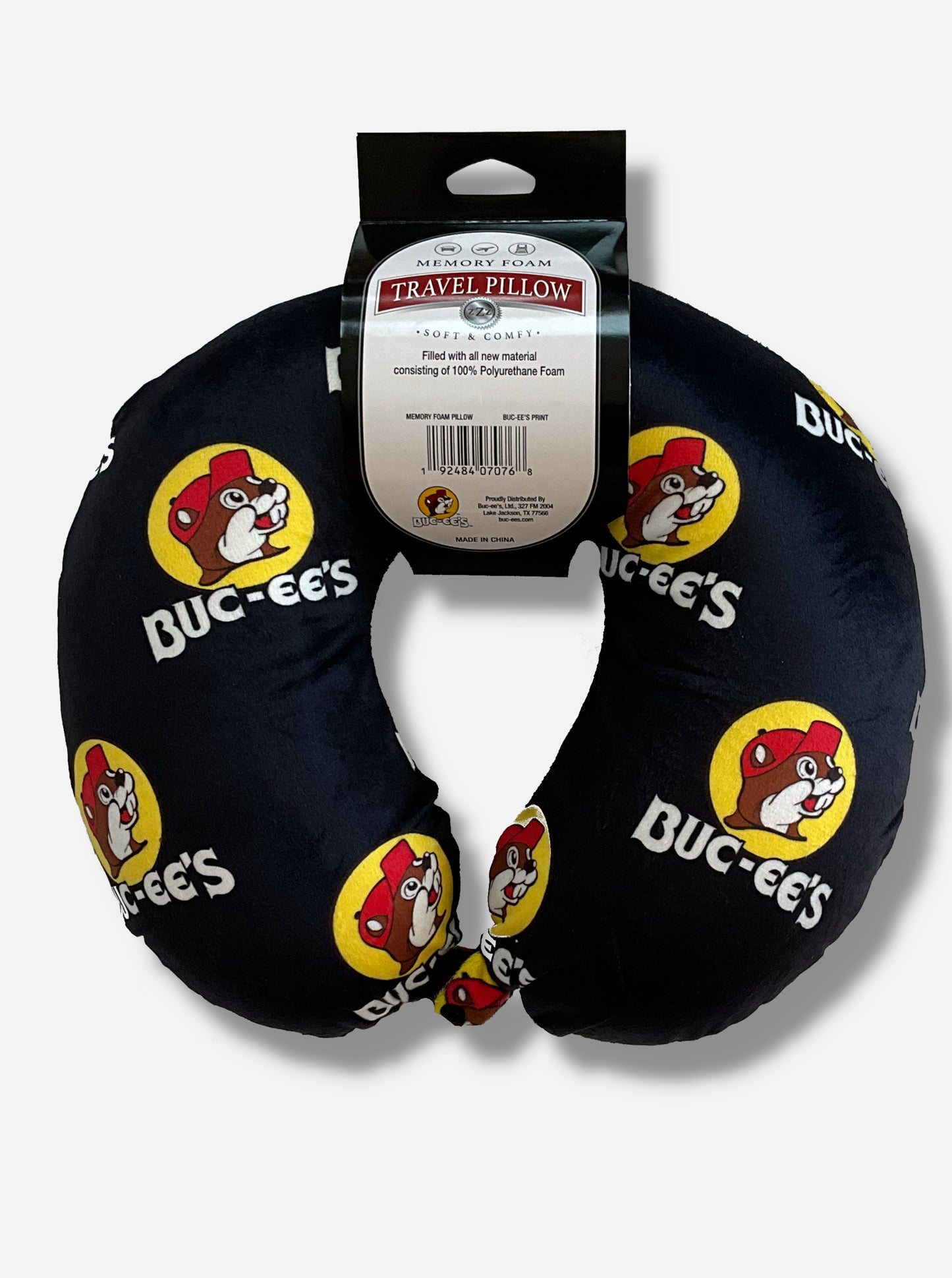 A picture of a u-shaped, memory foam travel pillow.  It is adorned with the Buc-ee The Beaver logo, and says BUC-EE'S underneath each logo.  The rest of the neck pillow is black.  The label on the pillow reads MEMORY FOAM TRAVEL PILLOW.  SOFT AND COMFY.  Filled with all new material consisting of 100% Polyurethane Foam.